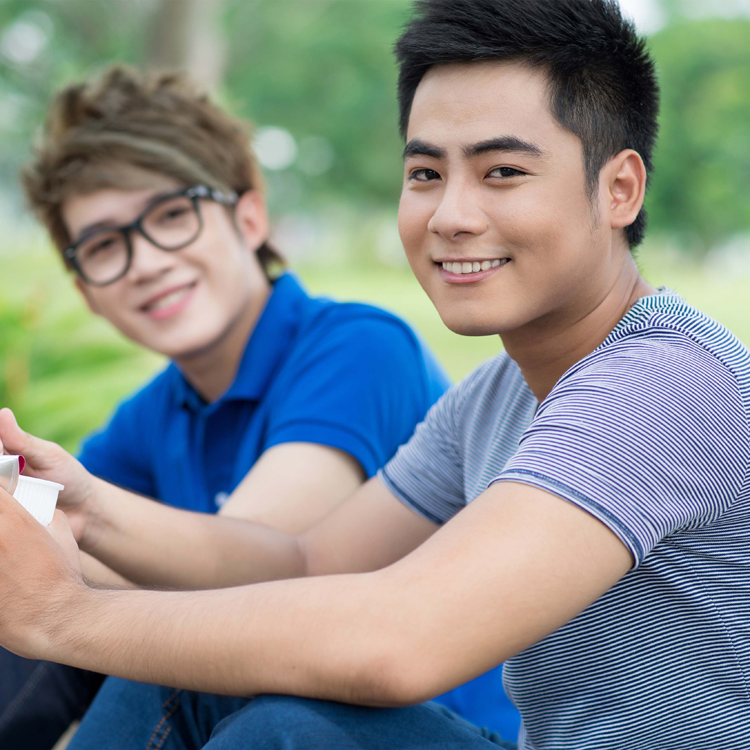 Two teenagers eating outside.