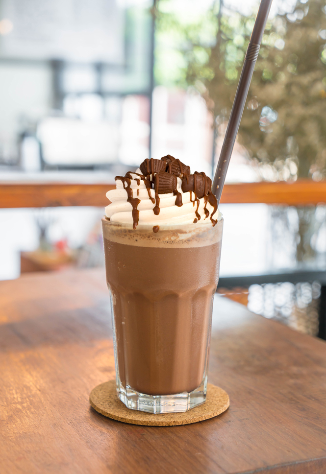 Chocolate peanut butter cup milkshake with whipped cream and mini chocolate peanut butter cups on top.